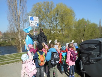 Kinder stehen in einer Gruppe mit gesammeltem Müll an der Saale.