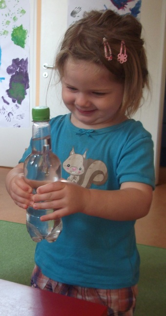 Die Kinder entdecken, dass der Flaschengeist beim Drücken der Flasche nach unten sinkt.