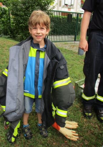 Ein Kind hat die Jacke eines Feuerwehrmannes an.