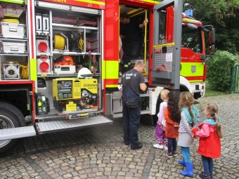 Die Kinder schauen sich ein Feuerwehrauto von innen an.