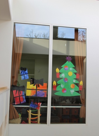 Ein gebastelter Weihnachtsbaum hängt an einem Fenster.
