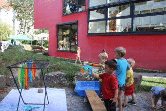Kinder zielen mit Spritzpistolen auf farbige Bänder