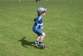 Ein Kind breitet auf Fußballplatz die Arme aus um den Ball zufangen. 