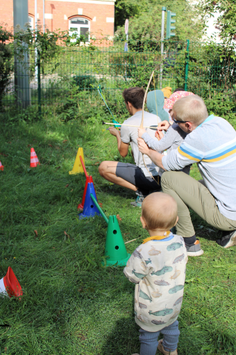 Kinder und Eltern probieren mit Pfeil und Bogen zu schießen.